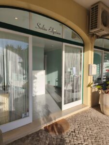 Salão Elysium building entrance with white curtains and a doormat